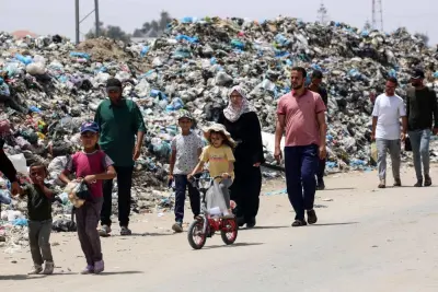 A young girl rides a bicycle as people walk past garbage piled up near tents set up by displaced Palestinians in Khan Yunis in the southern Gaza Strip on Saturday. AFP