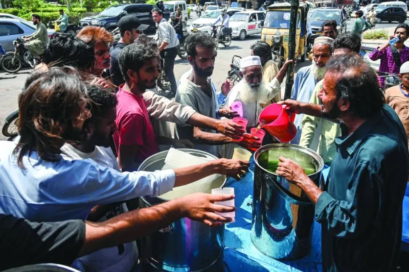 A volunteer distributes cold drinks to passers-by at a &#039;heatwave relief camp&#039; during a hot summer day in Karachi.