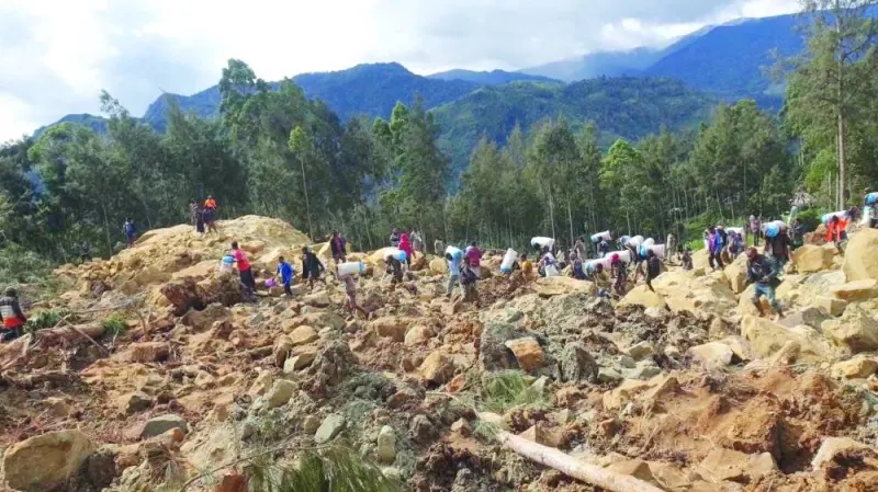 People carry bags in the aftermath of a landslide in Enga Province, Papua New Guinea, on Friday.