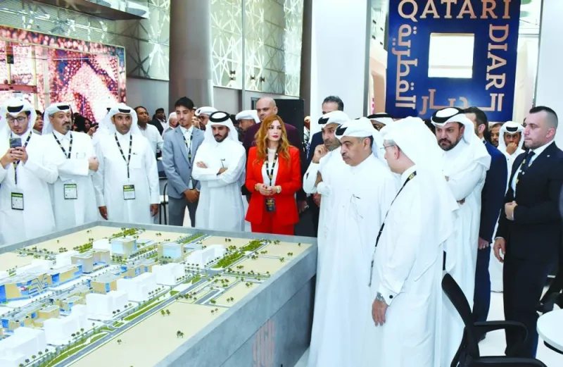 The minister listens to a briefing during a tour of the exhibition hall.