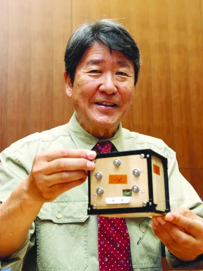 Takao Doi, an astronaut and special professor at Kyoto University, holds the world's first wooden satellite made from wood and named LignoSat during a press conference at the university's campus in Kyoto. (AFP)