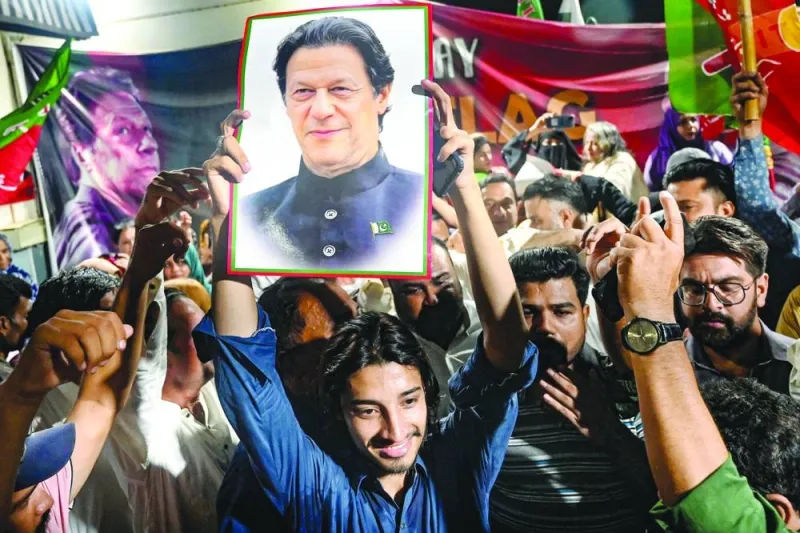 Supporters of Pakistan’s former prime minister Imran Khan hold his poster in Karachi as they celebrate his acquittal on Monday. (AFP)