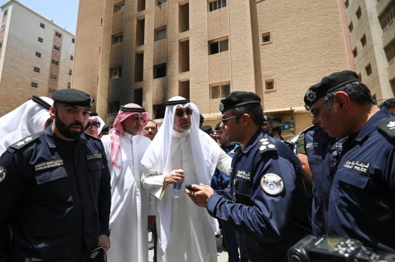 Deputy Prime Minister and Minister of Defense and acting Interior Minister, Fahad Yusuf Al-Sabah speaks with Kuwaiti police officers in front of a burnt building following a deadly fire, in Mangaf, southern Kuwait, on Wednesday. REUTERS