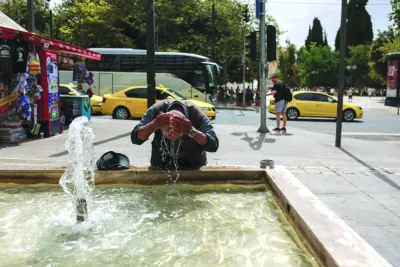 A man cools down with water from a fountain as a heatwave hits Athens.