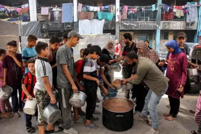 Children queue with pots to receive food aid from a kitchen at the Abu Zeitun school run by the UN Relief and Works Agency for Palestine Refugees (UNRWA) in the Jabalia camp for Palestinian refugees in the northern Gaza Strip.