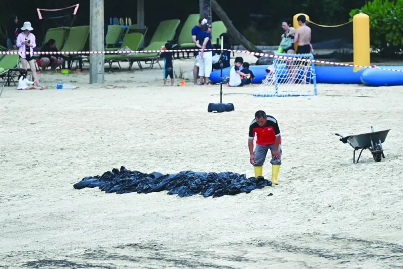 
A worker clears the oil slick in plastic bags on Sentosa island’s Siloso beach in Singapore. 