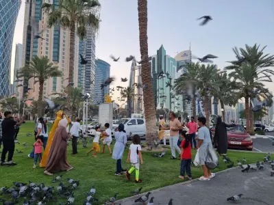 People feed pigeons on Doha Corniche Sunday while enjoying the Eid al-Adha holidays. PICTURE: Joey Aguilar.