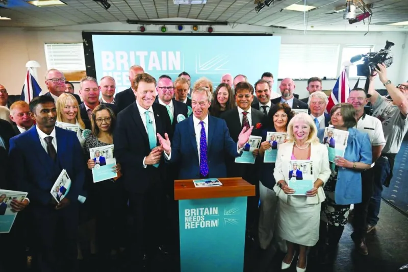 Reform UK leader Nigel Farage (centre), flanked by Reform UK party member Richard Tice signs the hard-right party's general election manifesto after launching it in Merthyr Tydfil, south Wales, yesterday.