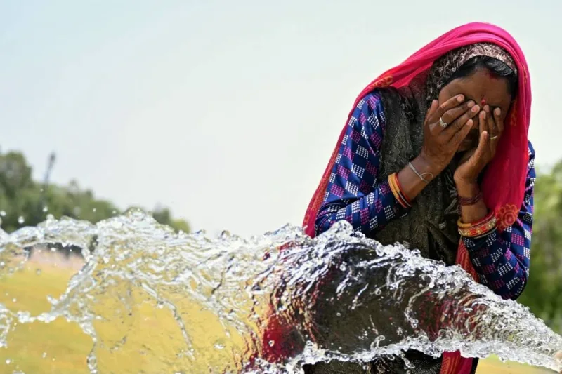 A woman washes her face with water to cool off during a hot summer day near the India Gate in New Delhi yesterday.