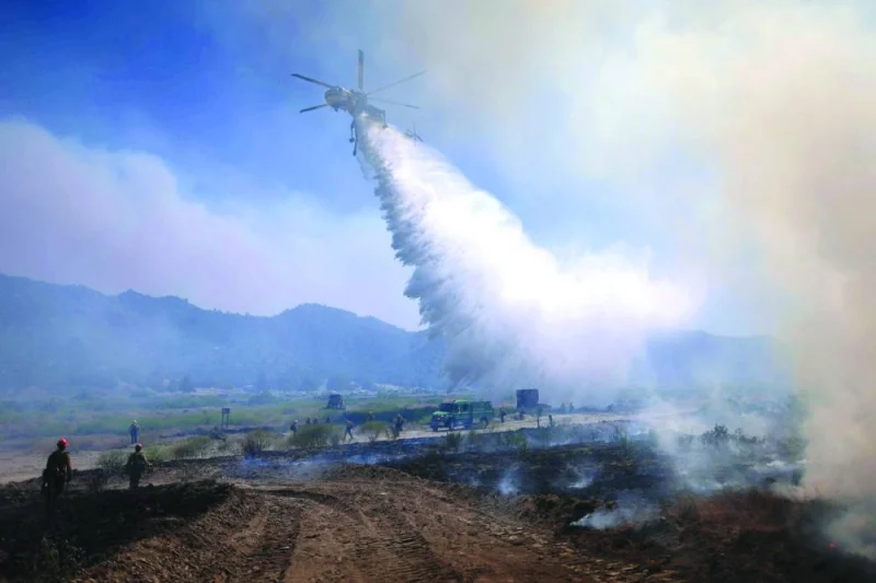 An air support aircraft drops water as the Post Fire burns through Castaic, California. (AFP)