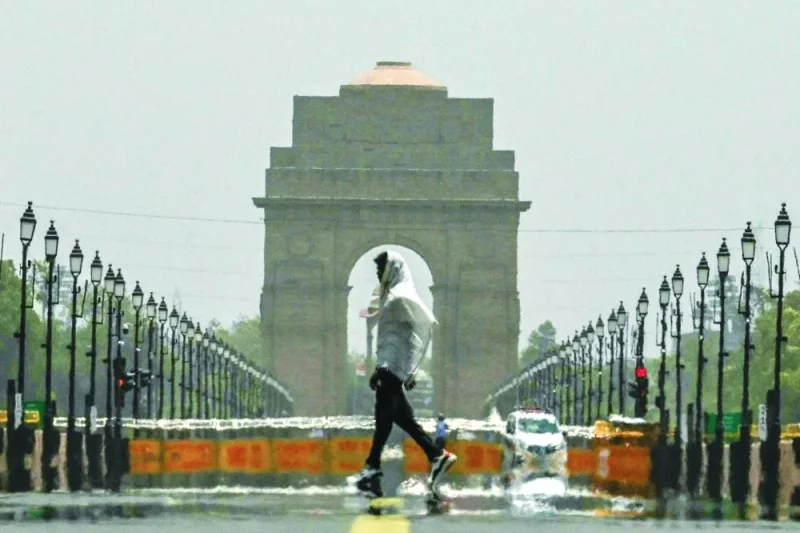 A man wears a scarf as he walks past the India Gate on a hot summer day in New Delhi yesterday