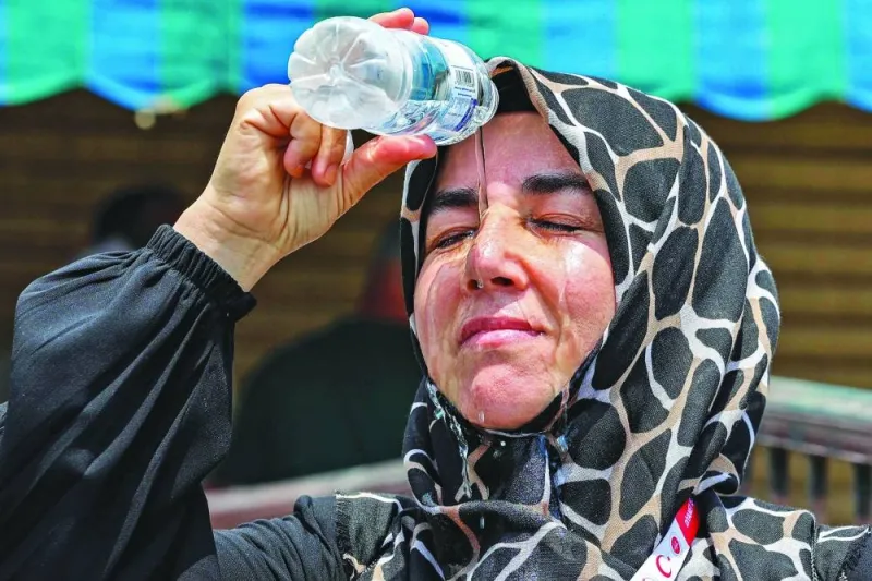 
A departing Turkish pilgrim pours cold water from a bottle on her head to cool off as she waits in Saudi Arabia’s holy city of Makkah. 