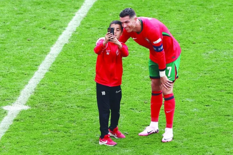 A pitch invader takes his selfie with Portugal’s Cristiano Ronaldo during the Euro 2024 match against Turkiye at the BVB Stadion in Dortmund on Saturday. (AFP)