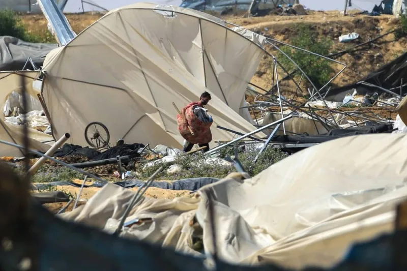 A man carries salvaged items following an Israeli raid in Rafah, on the southern Gaza Strip, on Saturday on a road damaged by Israeli bulldozers. AFP