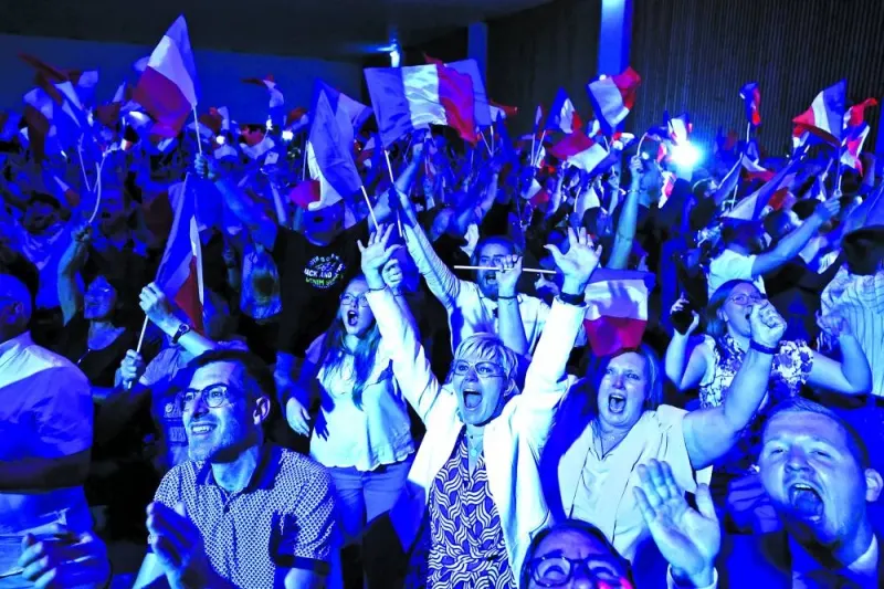 Supporters of National Rally party celebrate after partial results in the first round of the French parliamentary elections, in Henin-Beaumont, France, Sunday.
