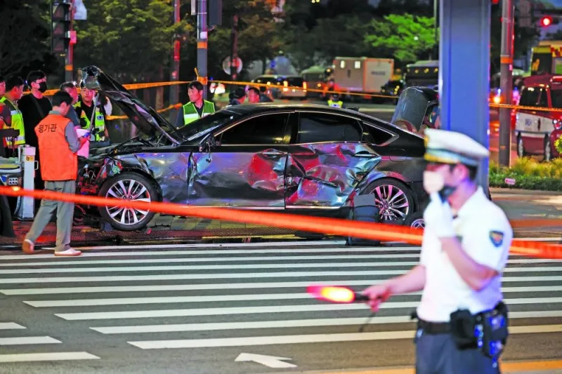 
Police and rescuers stand next to a car involved in accident that resulted in several people killed and injured in central Seoul, South Korea, yesterday. 