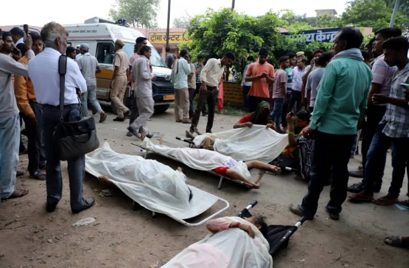 People stand next to the bodies of victims of a stampede outside a hospital in Hathras, Tuesday. REUTERS