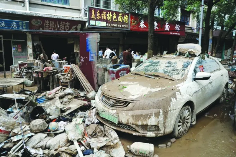A car and piles of debris are pictured on a street after a flood following heavy rainfall in Pingjiang county of Yueyang, Hunan province, China, on Wednesday.