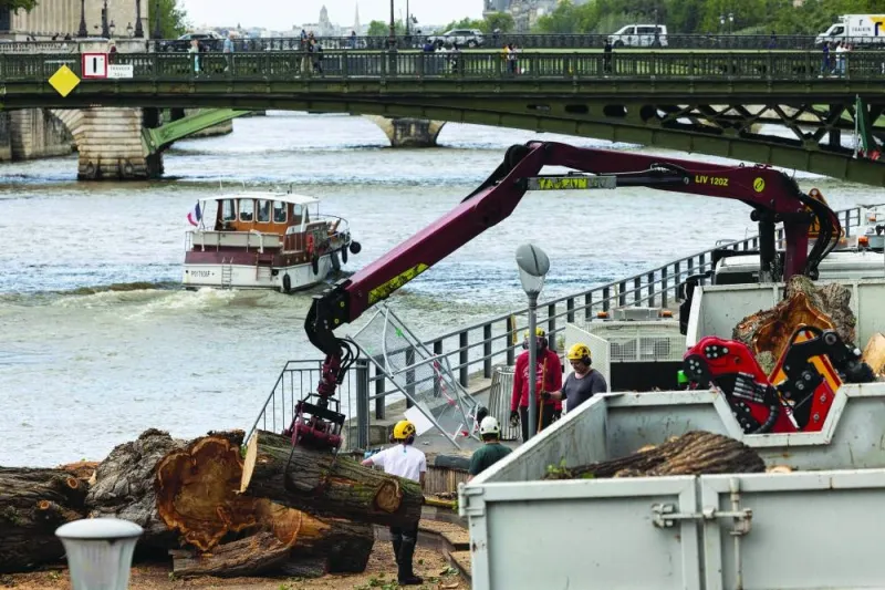 Employees working for the city of Paris remove cut down trees along the Seine River due to a risk of falling in preparation for the Paris 2024 Olympic Games opening ceremony, in Paris on Thursday. (AFP)