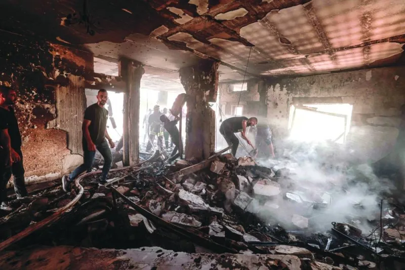People and rescue workers assess the damage inflicted on a house during an Israeli raid in the occupied West Bank city of Jenin, on Friday.