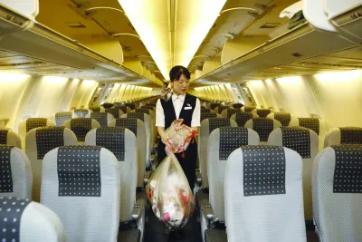 A cabin attendant carries bags of trash as she conducts her cleaning duties in the cabin of a Japan Airlines airplane at Haneda Airport in Tokyo (file). A growing challenge for airlines is the sustainable management of millions of tonnes of waste generated within the cabin.
