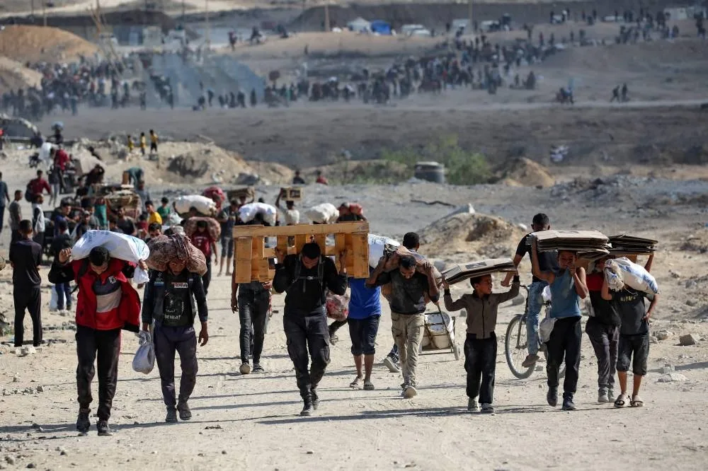 Palestinians carry bags, wooden pallets and empty cardboard boxes as they leave a food distribution point run by the US and Israeli-backed Gaza Humanitarian Foundation (GHF) group, near the Netsarim corridor in the central Gaza Strip, yesterday.