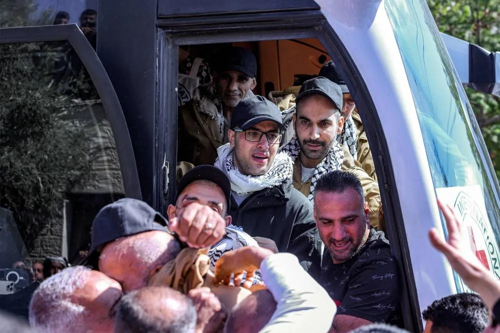 Palestinian prisoners released in a prisoner-hostage swap and ceasefire deal between Israel and Hamas disembark from their bus upon arrival at Ramallah Cultural Centre in Ramallah in the occupied West Bank, on October 13, 2025, coming from Ofer military prison in the Israel-occupied Palestinian territories. The initial stage of the Gaza ceasefire deal includes the release of 47 Israeli living and dead hostages taken on October 7, 2023 in exchange for 250 prisoners and 1,700 Gazans held by Israel since the war broke out. (Photo by Zain JAAFAR / AFP)