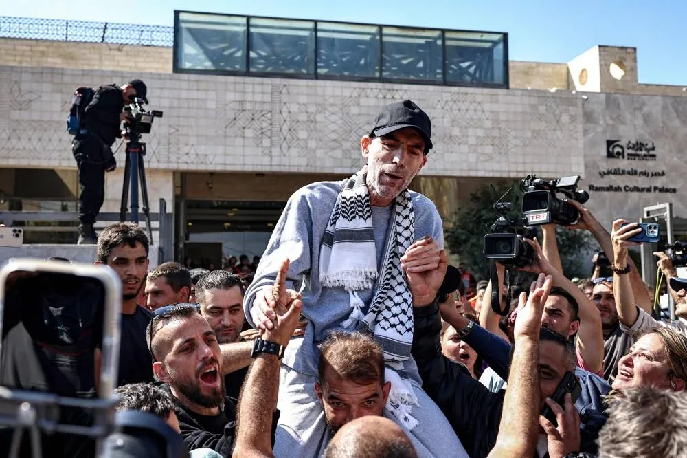 One of the Palestinian prisoners, who was released in a prisoner-hostage swap and ceasefire deal between Israel and Hamas, is carried on shoulders upon arrival by bus at Ramallah Cultural Centre in Ramallah in the occupied West Bank, on October 13, 2025, coming from Ofer military prison in the Israel-occupied Palestinian territories. The initial stage of the Gaza ceasefire deal includes the release of 47 Israeli living and dead hostages taken on October 7, 2023 in exchange for 250 prisoners and 1,700 Gazans held by Israel since the war broke out. (Photo by Zain JAAFAR / AFP)
