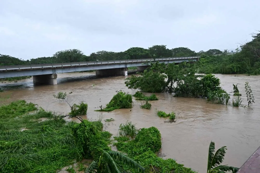 The Rio Cobre comes out of its banks near St. Catherine, Jamaica, on October 28, 2025. Ferocious winds and torrential rain tore into Jamaica Tuesday as Hurricane Melissa made landfall, the worst storm ever to strike the island nation and one of the most powerful hurricanes on record. The extremely violent Category 5 system was still crawling across the Caribbean, promising catastrophic floods and life-threatening conditions as maximum sustained winds reached a staggering 185 miles per hour (295 kilometers per hour). (AFP)