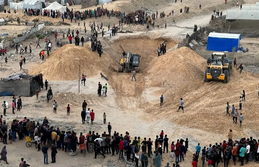 People gather during the search for the bodies of deceased hostages, in Khan Younis, southern Gaza Strip, yesterday
