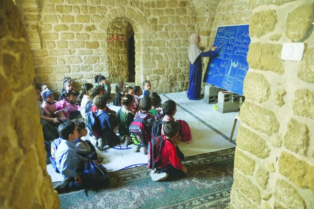 Palestinian children attend a class in the historic "Al-Kamaliya al-Othmanya" school in Gaza City's Old Town, as part of a volunteer initiative organized by displaced teachers, in Gaza City on November 2, 2025. (Photo by Omar AL-QATTAA / AFP)