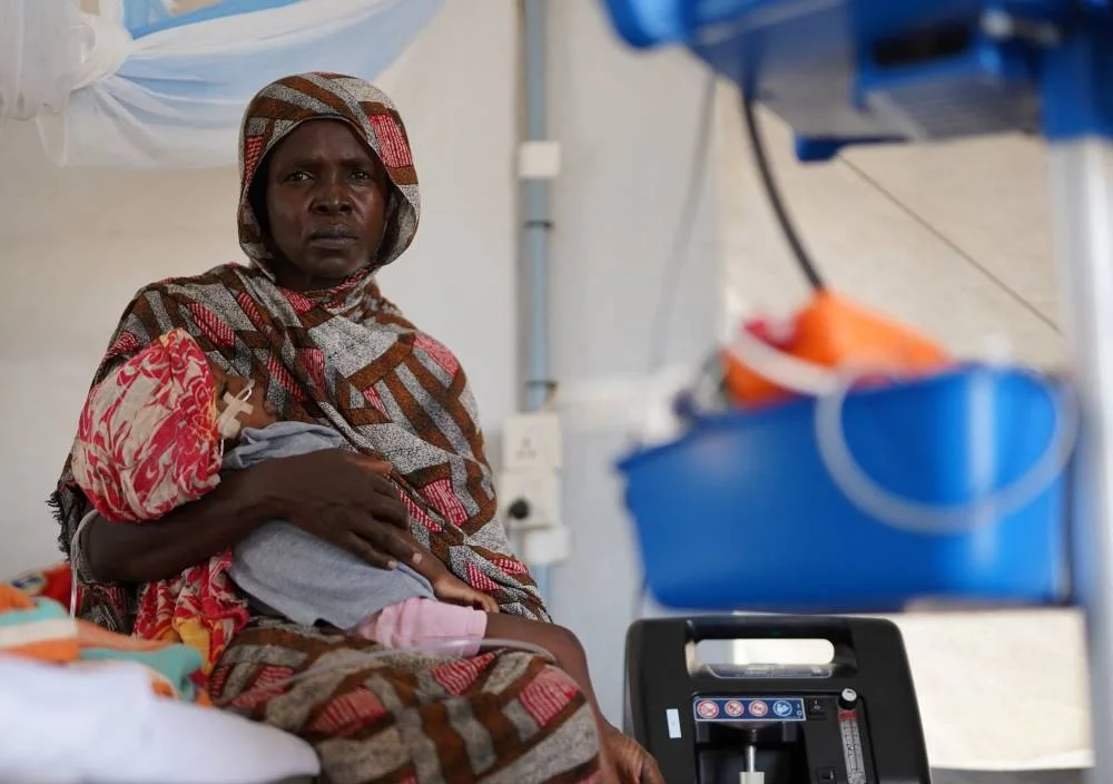 An injured displaced Sudanese woman who fled violence in El-Fasher receives treatment while carrying her child at a makeshift clinic run by Medecins Sans Frontieres (MSF), in Tawila, North Darfur, on Monday. REUTERS