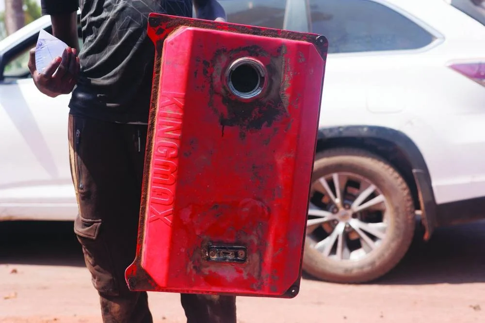 A man shows an empty jerry can in Bamako, on October 28, 2025. In Bamako's business district hundreds of cars and motorcycles crowd a boulevard day and night, waiting for one of the three gas stations to finally dispense fuel. The Malian capital is suffering under a blockade imposed by jihadists, making daily life extremely difficult for residents. Since September the Group for the Support of Islam and Muslims (JNIM), affiliated with Al-Qaeda, has been targeting fuel tankers, particularly those coming from Senegal and Ivory Coast through which the majority of goods imported into Mali transit. (Photo by AFP)
