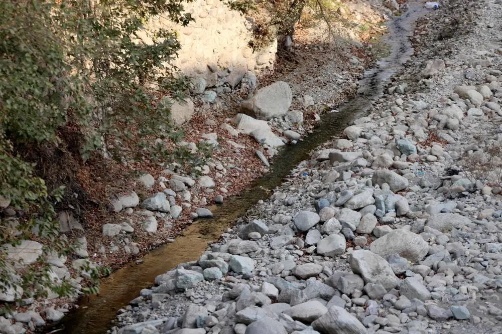 A trickle of water flows in the mainly dried-up Kan River, west of Tehran, Sunday.