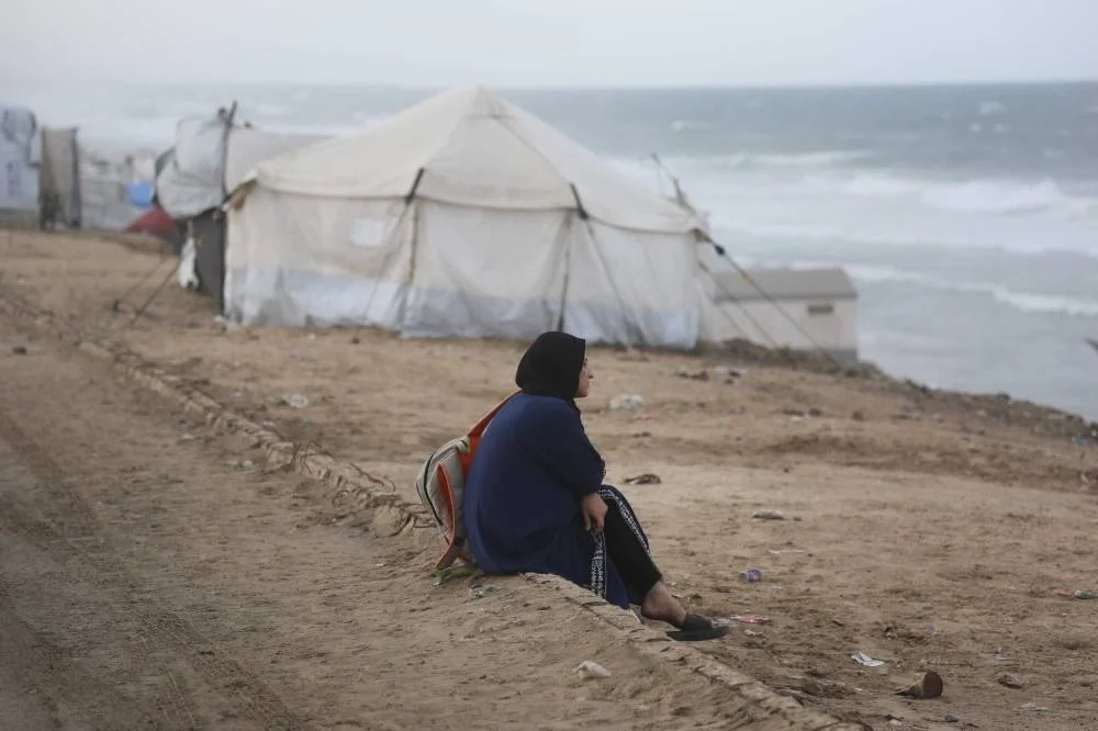 A displaced Palestinian woman sits on the beach near tents west of Deir al-Balah city in the central Gaza Strip, on November 15, 2025 as a low-pressure system impacts the area. (AFP)