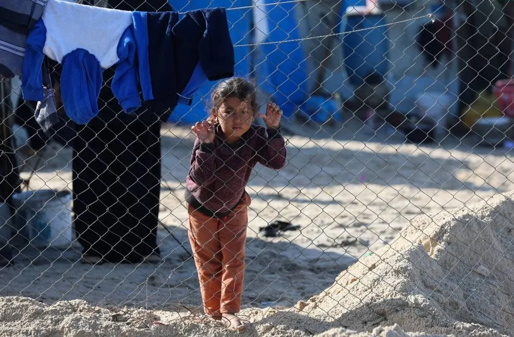 A child leans on a fence as Palestinians take shelter in their tents, amid a ceasefire between Israel and Hamas, in Khan Younis, southern Gaza Strip, November 15, 2025. REUTERS