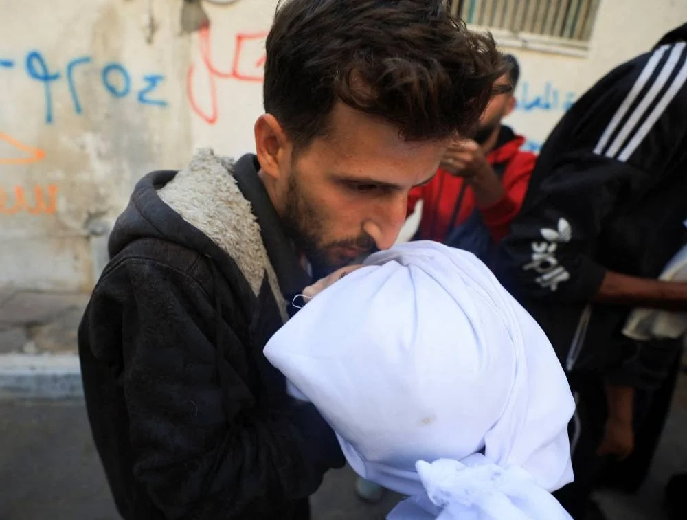 A mourner holds the body of a Palestinian who, according to medics, were killed in overnight Israeli strikes, during a funeral at Al-Shifa Hospital in Gaza City, November 20, 2025. REUTERS