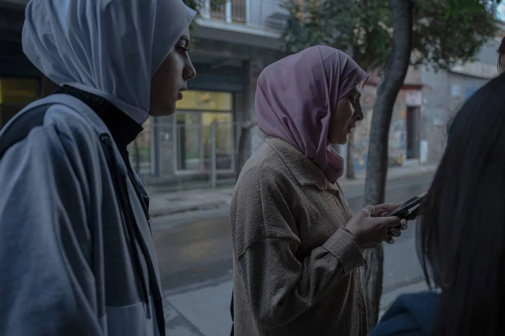Palestinian refugees Raghad al-Fara, 15 (left) and her mother Shadia al-Fara, 44 (centre), who now live in Athens, stand outside a refugee shelter.