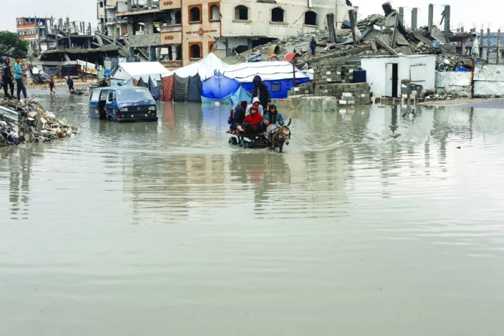 Displaced Palestinians ride a donkey-drawn cart on a rain-flooded street in Gaza City, yesterday.