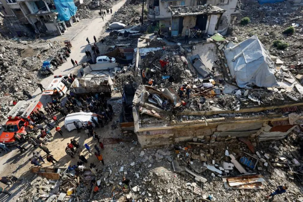 People gather during a search and rescue operation at the site of a house that was partially destroyed during the war and collapsed on Tuesday, at Shati refugee camp in Gaza City, December 16, 2025. REUTERS
