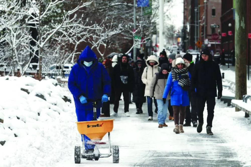 People walk through the snow in Brooklyn after an overnight storm in New York City, Saturday.