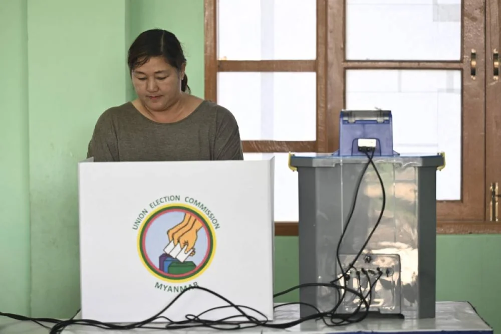 A voter casts her ballot using an electronic voting booth at a polling station during the first phase of Myanmar's general election in Naypyidaw on December 28, 2025. (AFP)