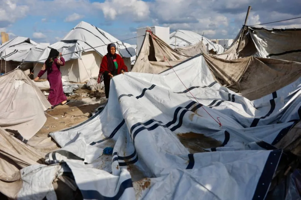 A displaced Palestinian woman adjusts the canvas of the family tent shelter as the region experiences rain and cold winter conditions, in Gaza City an December 28, 2025. The majority of Gaza's 2.4 million people have been displaced, often multiple times, by the war that began with Hamas's attack on southern Israel on October 7, 2023. With many displaced living in tent camps, raising serious concerns over winter. (AFP)