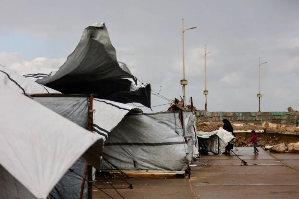 A displaced Palestinian woman adjusts the canvas of the family tent shelter as the region experiences rain and cold winter conditions, in Gaza City an December 28, 2025. The majority of Gaza's 2.4 million people have been displaced, often multiple times, by the war that began with Hamas's attack on southern Israel on October 7, 2023. With many displaced living in tent camps, raising serious concerns over winter. (AFP)