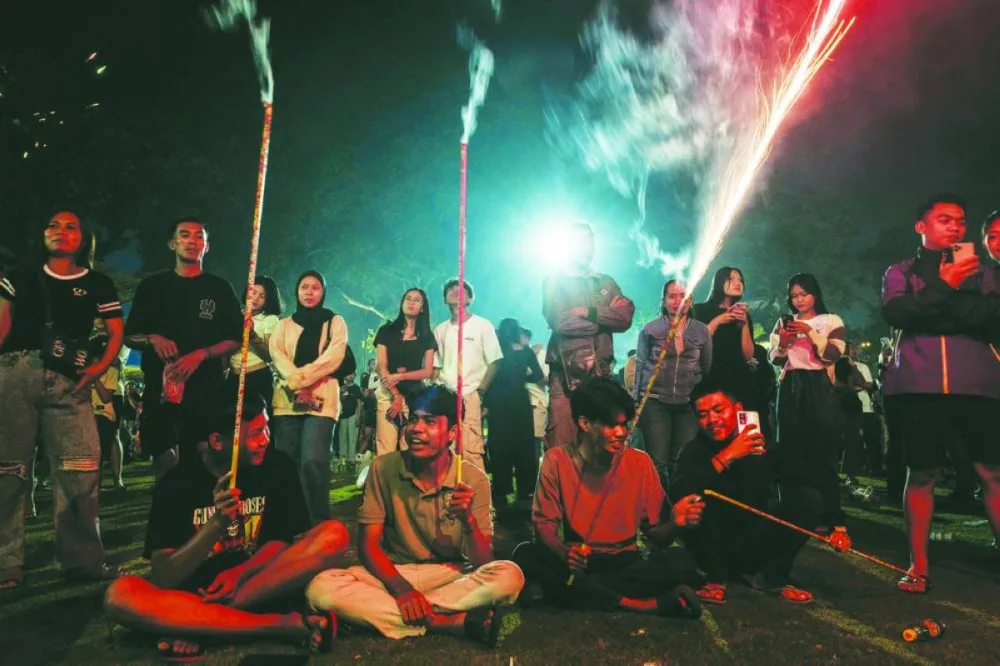 People hold fireworks to celebrate the New Year at Alun-Alun Kota Gianyar in Bali, Indonesia. 
