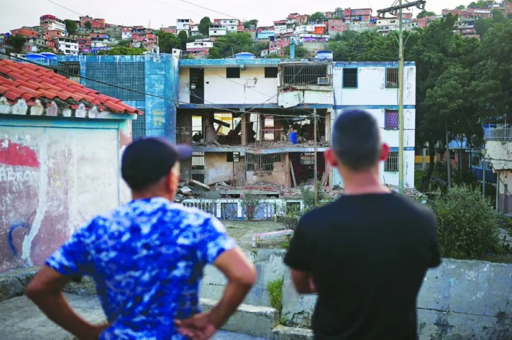 Two men looks at their damaged apartment building, after the US launched a strike on Venezuela, capturing its President Nicolas Maduro and his wife Cilia Flores, in Catia La Mar, Venezuela, Sunday.