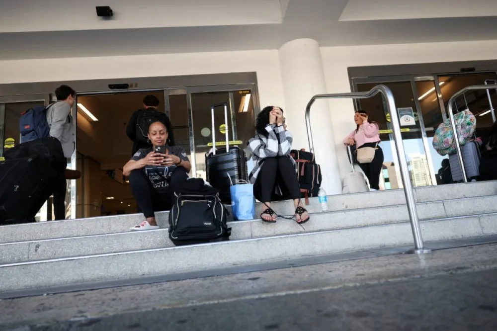 Passengers rest on the ground, after flights were delayed and cancelled when the airspace was closed due to U.S. strikes on Venezuela overnight, at Luis Munoz Marin International Airport in Carolina, near San Juan, Puerto Rico. REUTERS