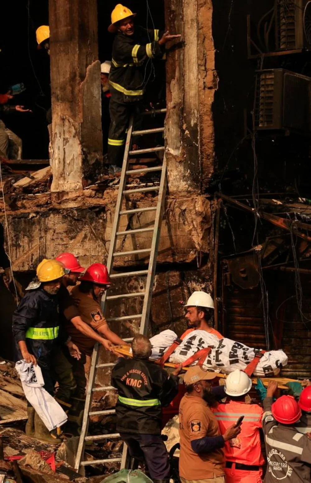 Emergency personnel remove human remains from the Gul Plaza Shopping Mall in Karachi. – Reuters