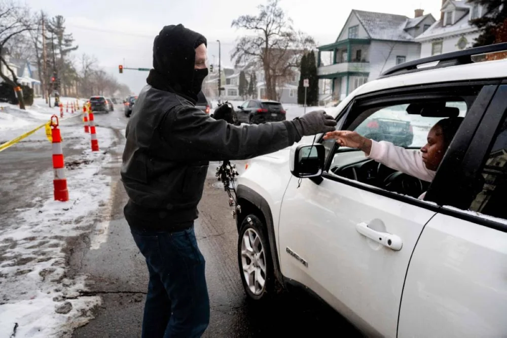 A man hands out whistles to people in cars passing by the memorial in Minneapolis for Renee Good. Residents of the city have taken to blowing whistles every time they spot ICE agents in the streets of the city. – AFP