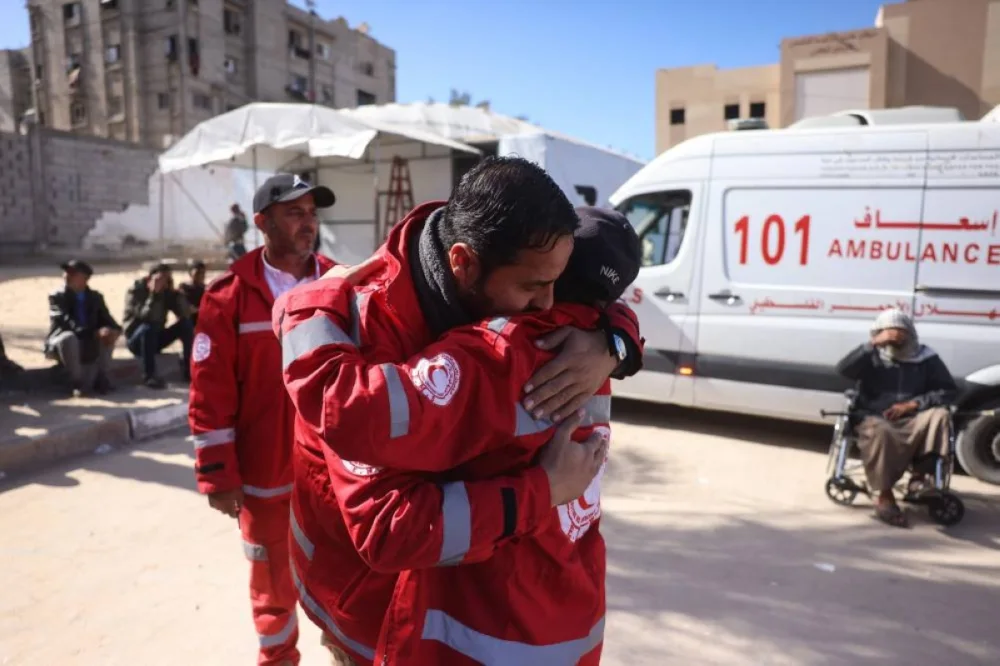 Members of the Palestinian Red Crescent comfort one another during the funeral of a colleague who was reportedly killed in an Israeli strike on a camp housing displaced Palestinians, in Khan Yunis in the southern Gaza Strip on February 4, 2026. Gazan health officials said Israeli air strikes on February 4, killed 21 people in the Palestinian territory, with Israel's military saying it struck after gunfire targeting its troops wounded an officer. Despite a US-brokered truce entering its second phase last month, violence has continued in the Gaza Strip, with Israel and Hamas accusing each other of breaching the agreement. (Photo by Bashar Taleb / AFP)